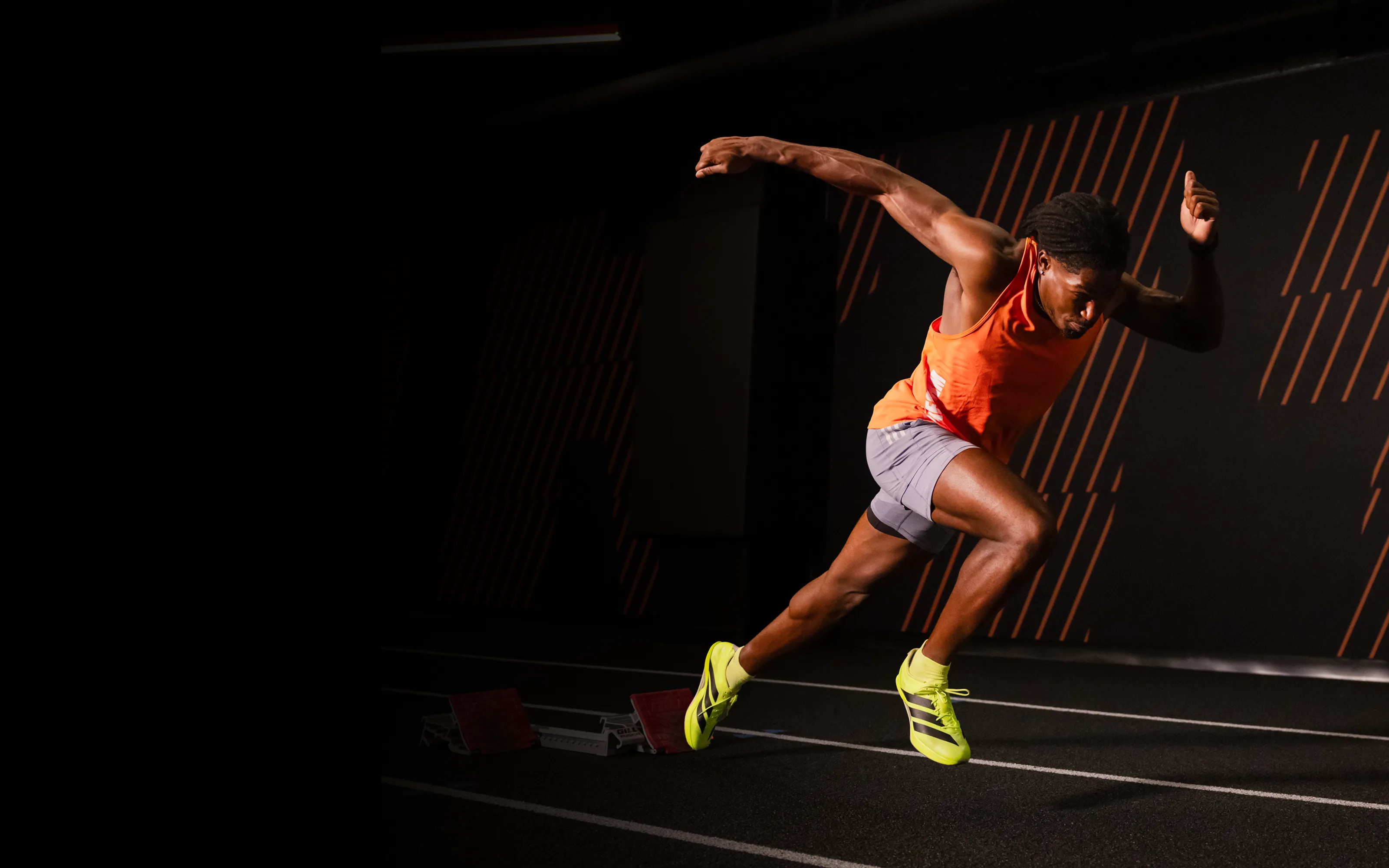 Outperform athlete driving out of starting blocks indoors