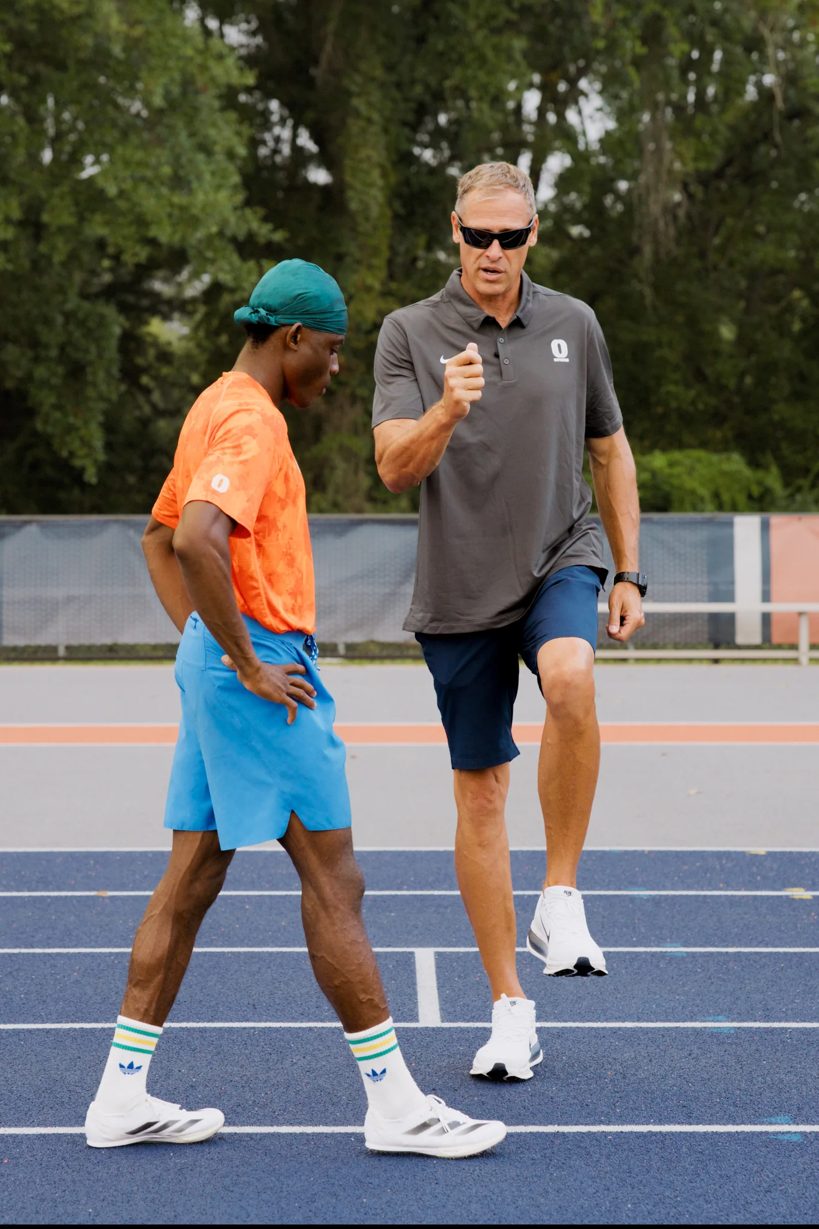 Ken Harnden demonstrating knee drive to a sprinter on the track